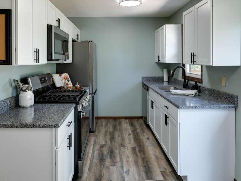 Updated kitchen with granite countertops, white shaker cabinets & gas range