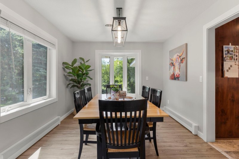 The bright dining area is framed by windows and illuminated by an updated light fixture, creating an inviting setting for meals and gatherings
