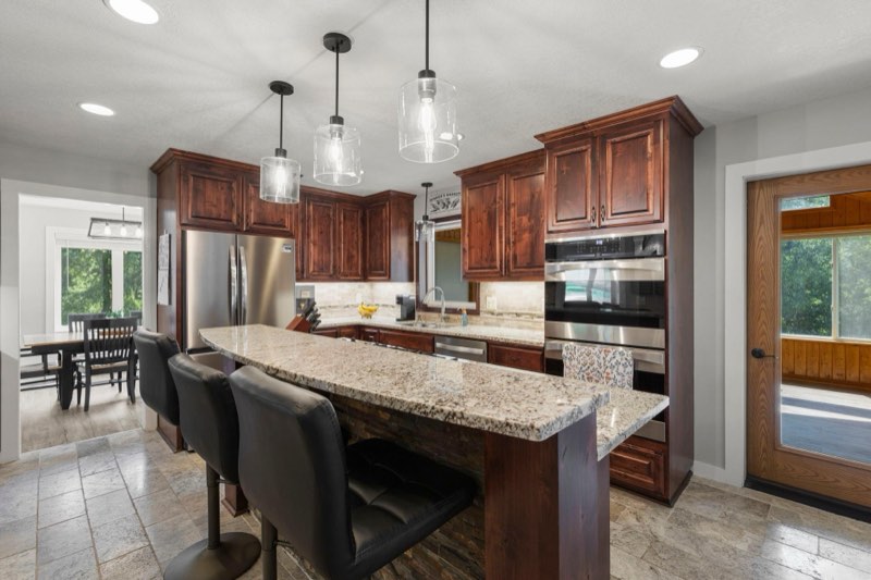 The beautiful kitchen features stainless appliances, island seating, double oven and access to the sunroom
